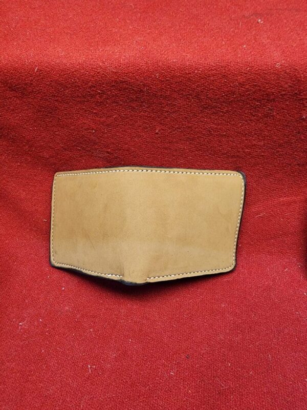 20231221_184428 Tan leather wallet on red fabric background.
