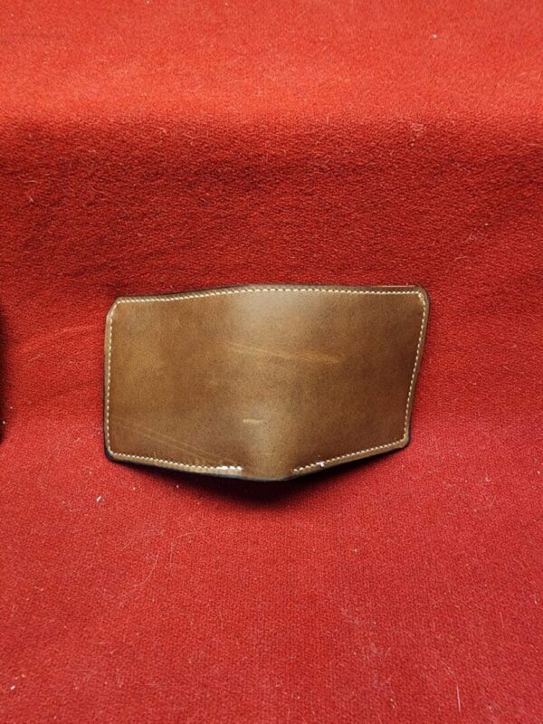 20231221_184431 Brown leather wallet on red fabric background.