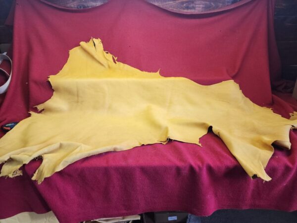 Yellow leather hide on red fabric background.