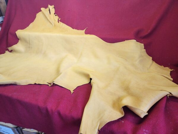 Yellow leather hide on red fabric background.