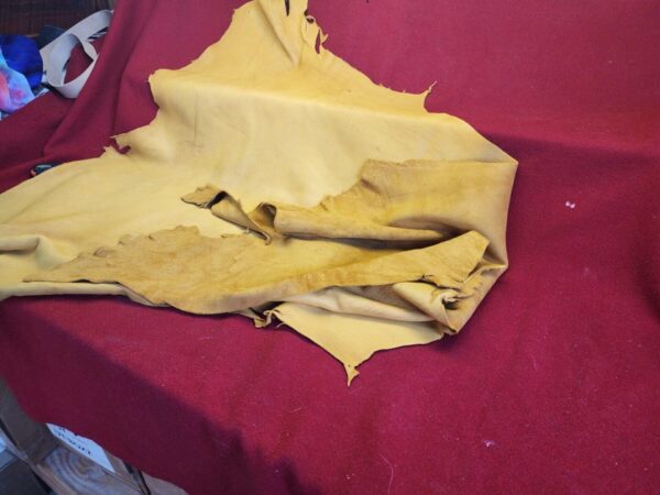 Yellow leather piece on red fabric background.