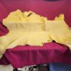 Yellow leather hide on red fabric background.