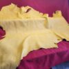 Yellow leather hide on red fabric background.
