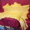 Yellow leather hide on red fabric background.
