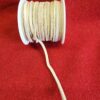 Beige suede cord spool on red fabric.