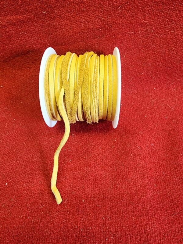 Yellow suede cord spool on red fabric.