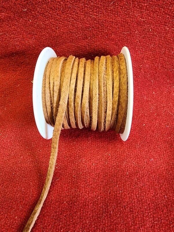 Brown suede cord spool on red fabric.