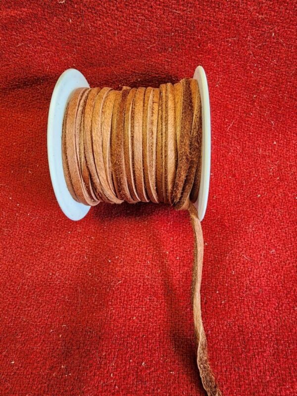 Brown leather cord spool on red fabric.