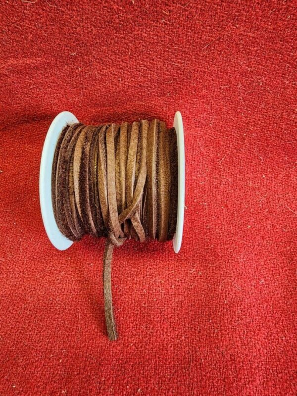 Brown leather cord spool on red fabric.