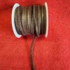 Brown leather cord spool on red fabric.