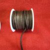 Brown leather cord spool on red background.