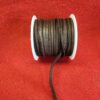 Spool of black leather cord on red.