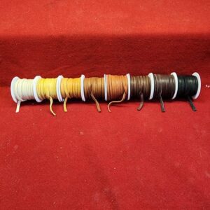 20240106_095803 Colored threads on spools against red background.