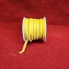 Yellow ribbon spool on red fabric background.