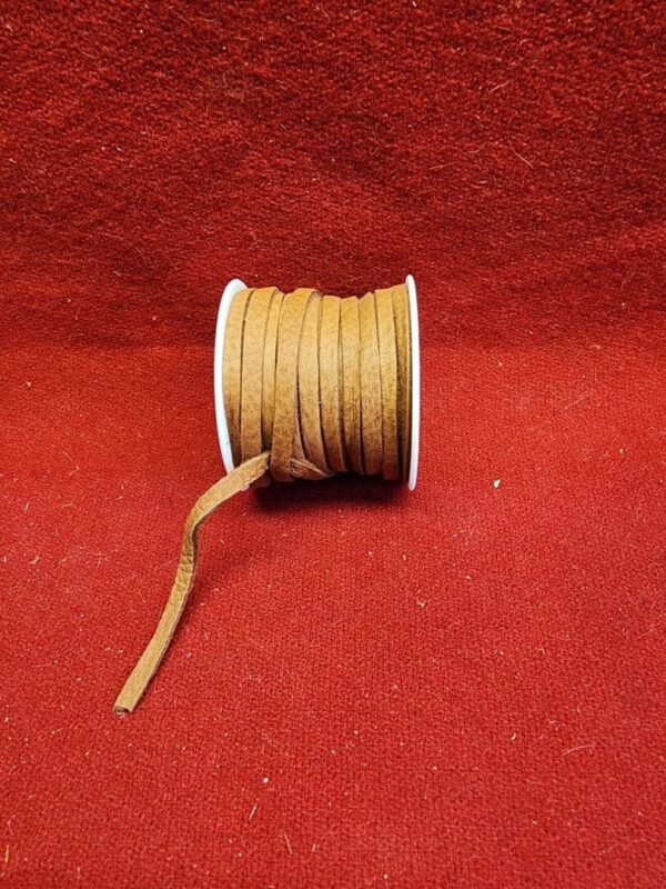 Brown leather cord spool on red fabric.
