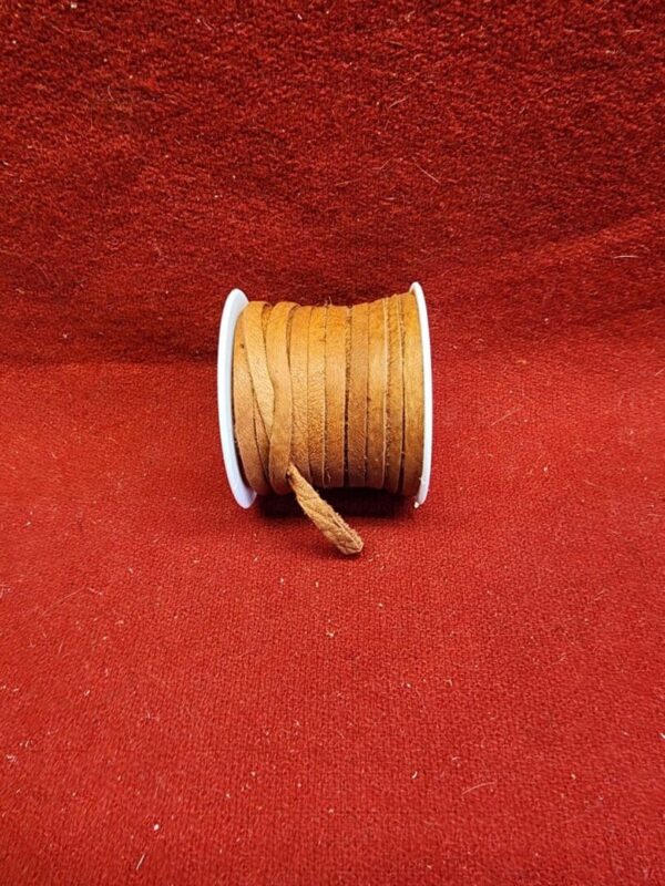 Brown suede cord spool on red background.