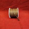 Brown ribbon spool on red fabric background.