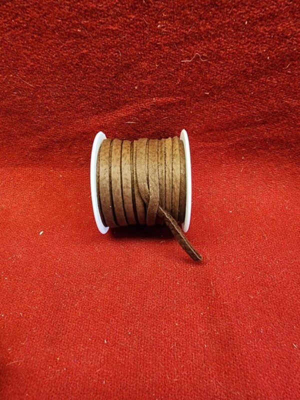 Brown ribbon spool on red fabric background.