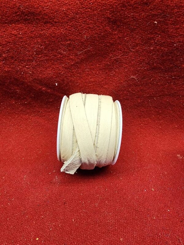 Roll of beige fabric ribbon on red.