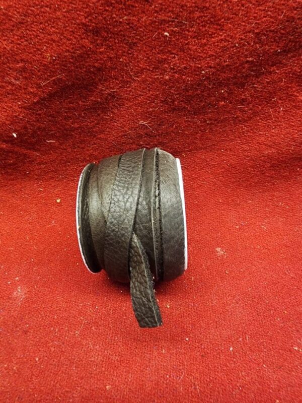 Black leather cord on red fabric background.