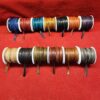 Colorful leather cords on spools, red background.