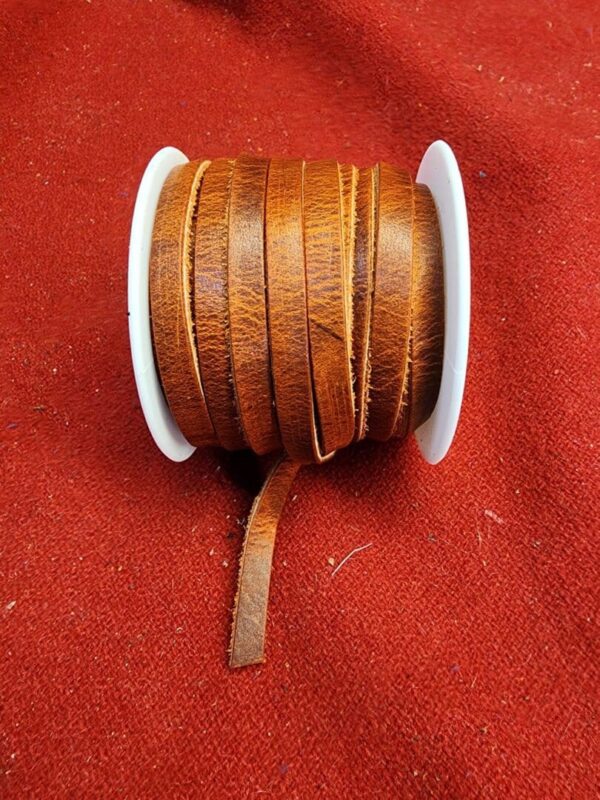 Brown leather strip on white spool.