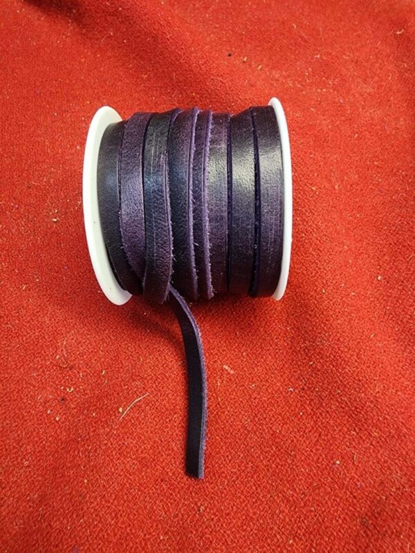 Purple leather cord spool on red fabric.