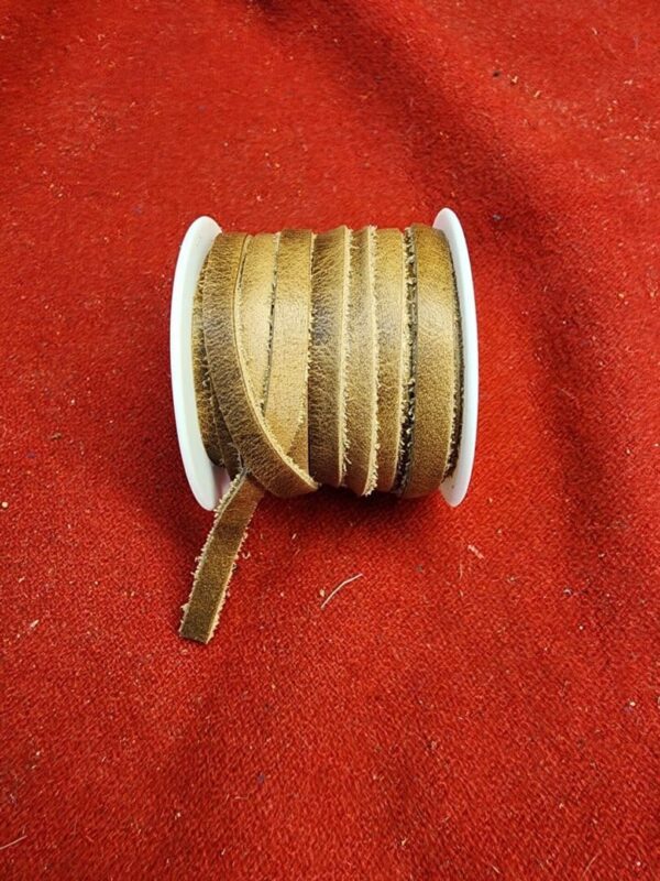 Brown ribbon spool on red fabric background.