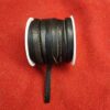 Black leather cord spool on red fabric.