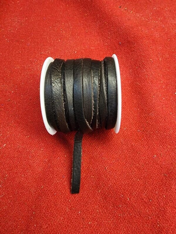 Black leather cord spool on red fabric.