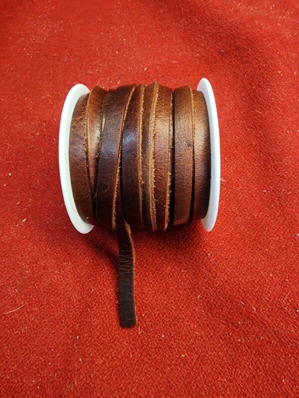Brown leather cord spool on red fabric.