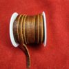 Brown leather ribbon spool on red fabric.