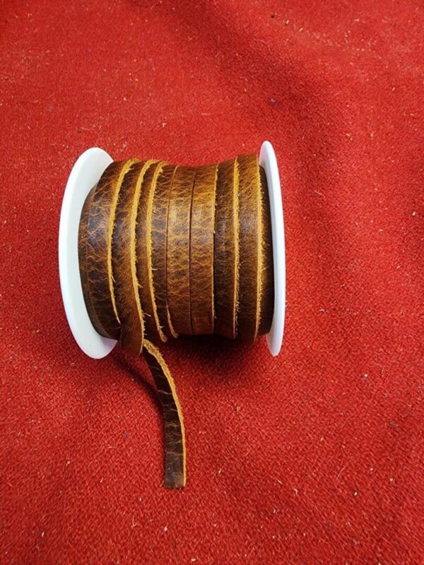 Brown leather ribbon spool on red fabric.