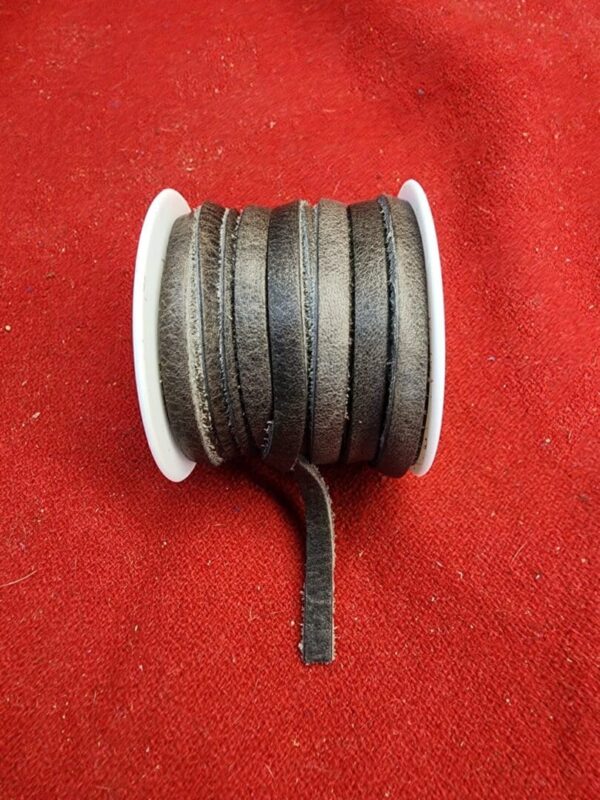 Leather cord spool on red fabric.