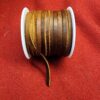 Brown leather cord spool on red fabric.