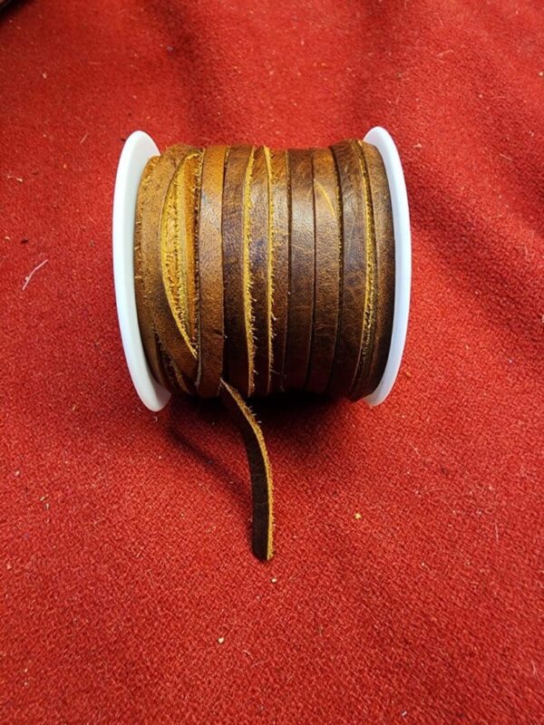 Brown leather cord spool on red fabric.