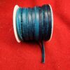 Blue leather cord spool on red fabric.