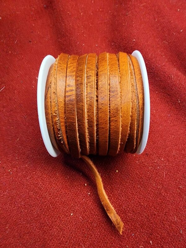 Brown leather cord spool on fabric.