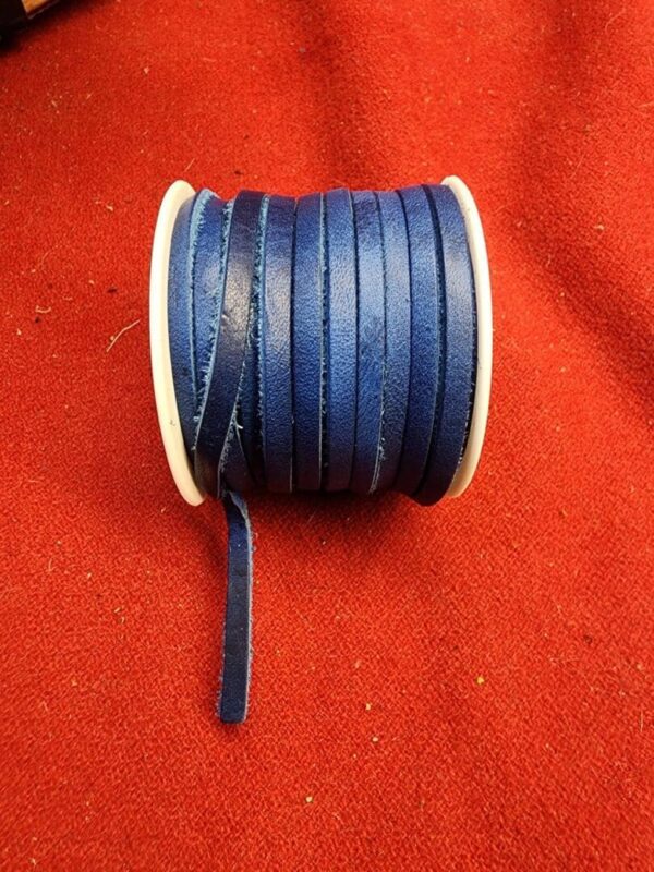 Blue leather cord spool on red fabric.