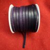 Purple leather cord spool on red fabric.