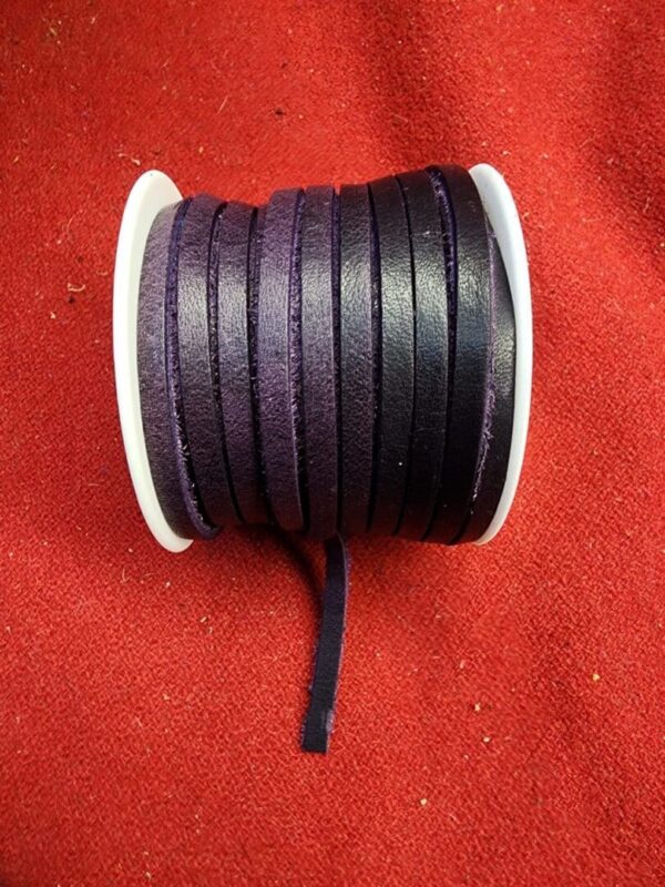 Purple leather cord spool on red fabric.