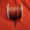 Brown leather cord spool on red fabric.