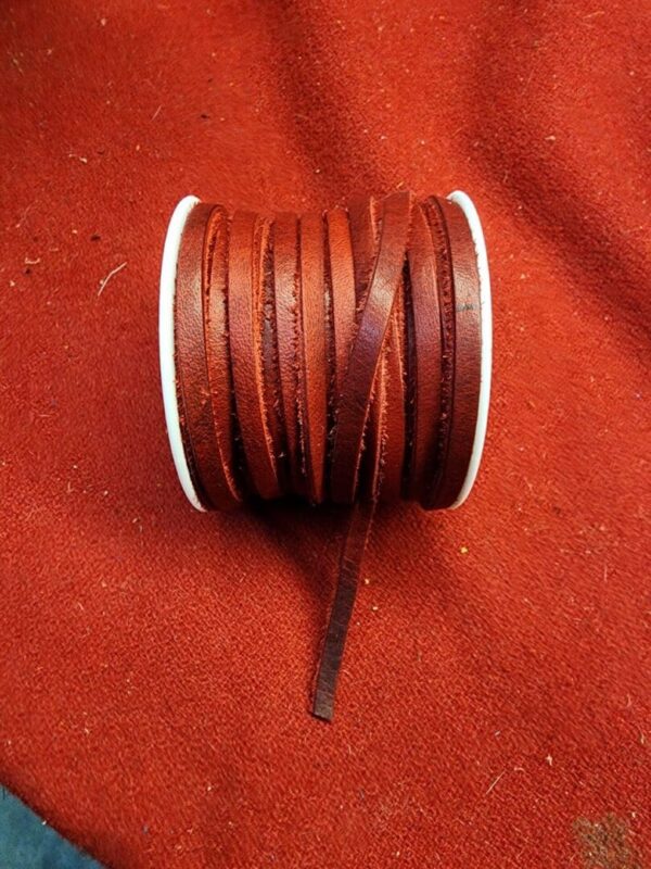 Brown leather cord spool on red fabric.