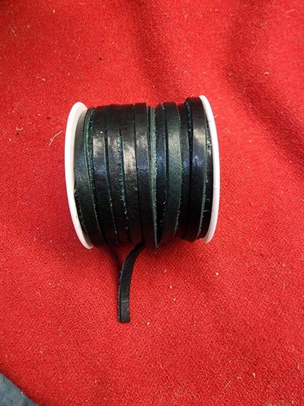 Black ribbon spool on red fabric background.