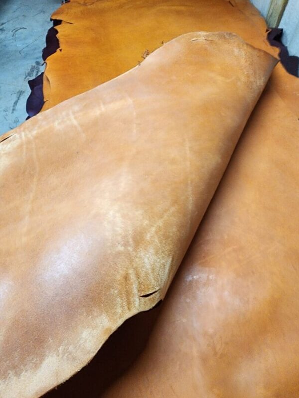 Brown leather hides stacked on floor.