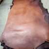 20240215_180547 Brown leather hides stacked on floor.
