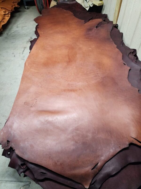 20240215_180547 Brown leather hides stacked on floor.