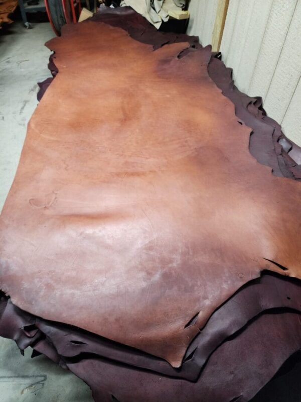 20240215_180555 Brown leather hides stacked in workshop.