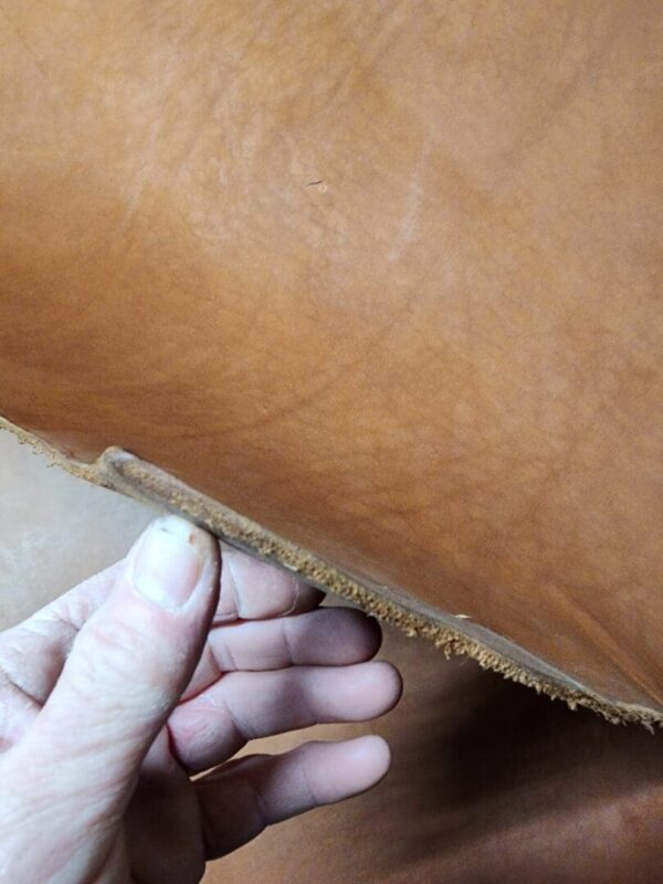 Hand holding a piece of brown leather.
