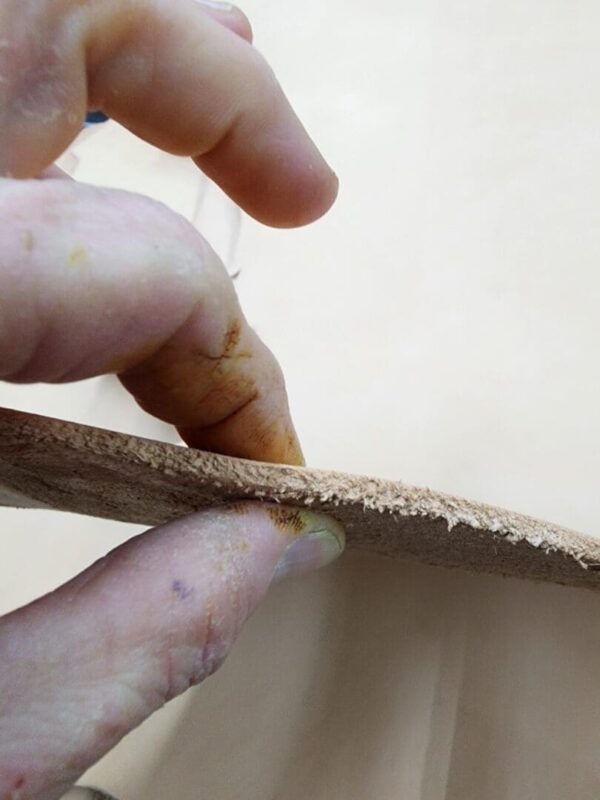 Hand holding a piece of leather edge.